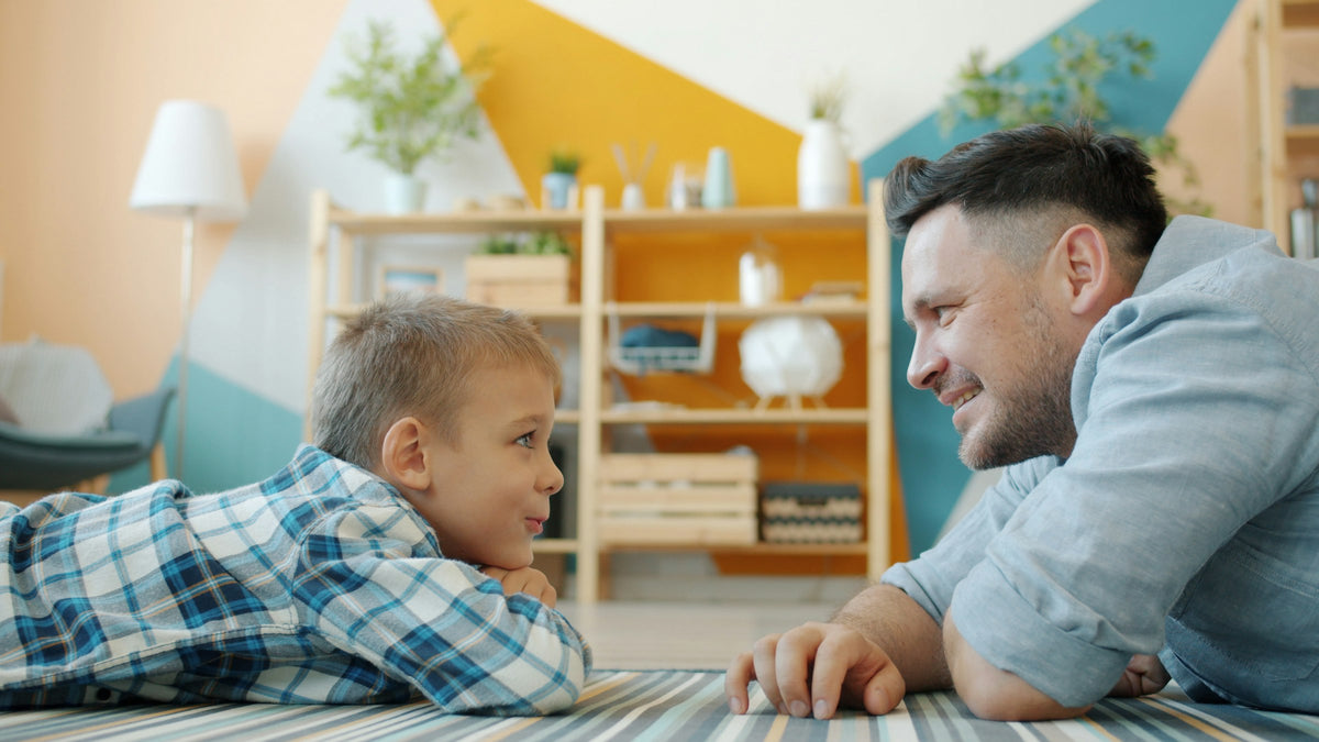 Vater und Sohn liegen auf dem Boden und lachen sich an